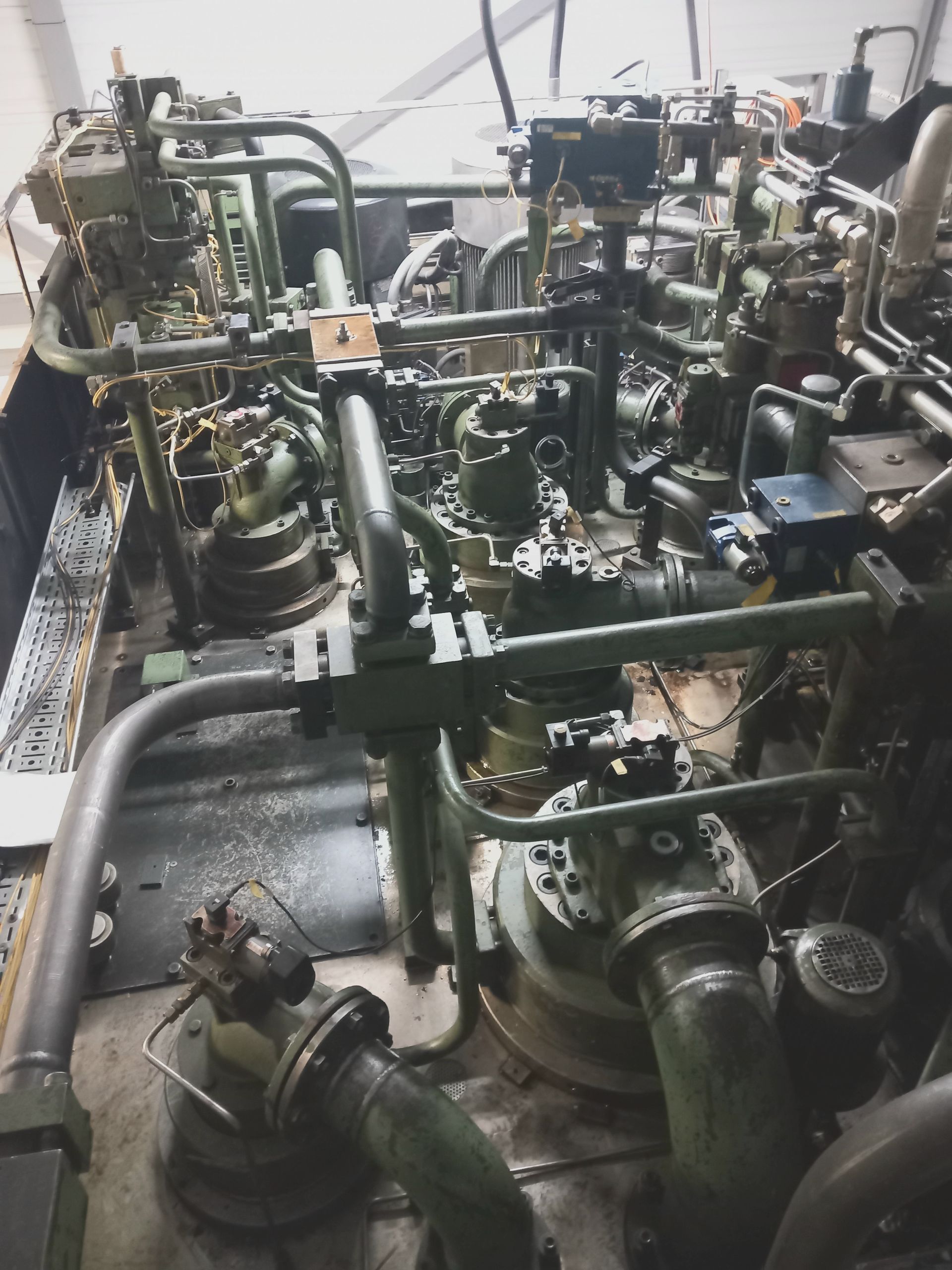 Machines industrielles avec tuyaux verts et vannes métalliques dans une salle d'usine exiguë