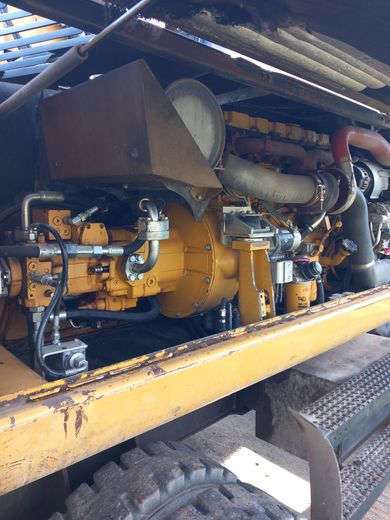 Moteur d'engin lourd jaune sous un auvent métallique, laissant apparaître tuyaux, conduites et gros composants.
