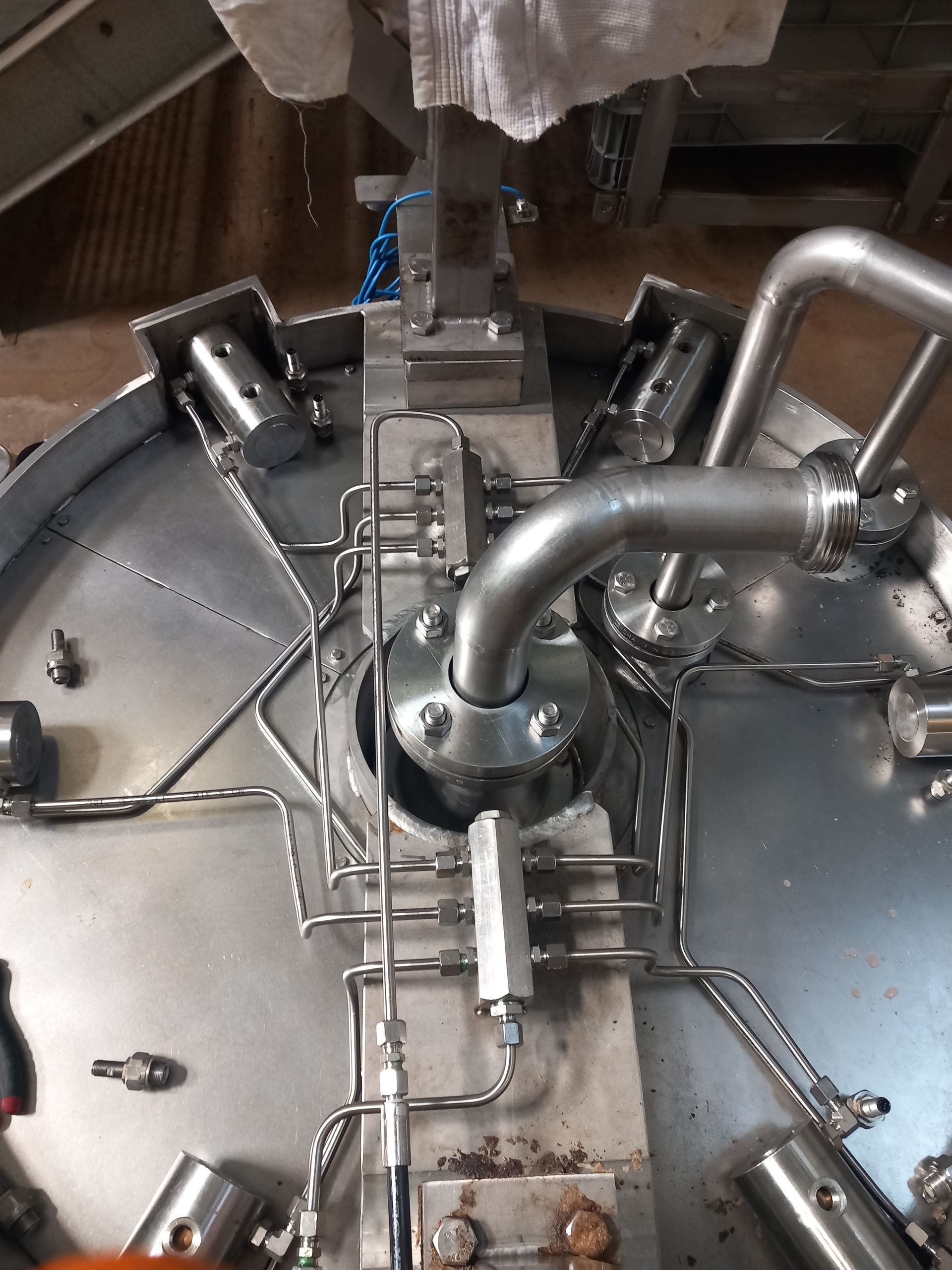 Intérieur d'un réservoir industriel en acier inoxydable avec tuyaux, vannes et buses de pulvérisation métalliques.