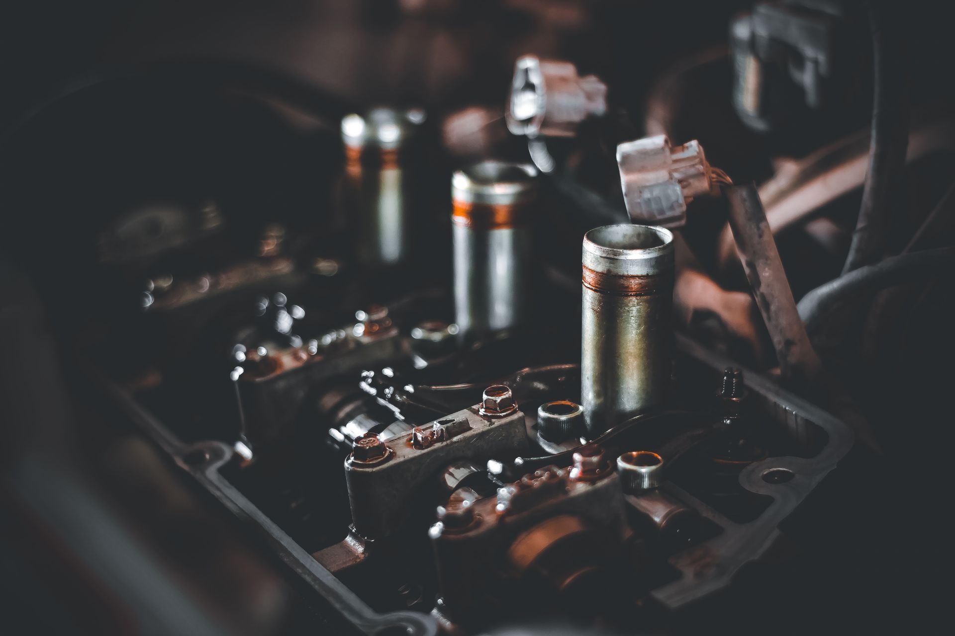 Gros plan sur un moteur de moto avec des composants métalliques et des câbles apparents dans un atelier sombre
