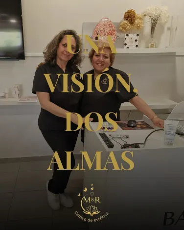 Dos mujeres vestidas de negro, sonrientes, están de pie dentro de un local comercial.