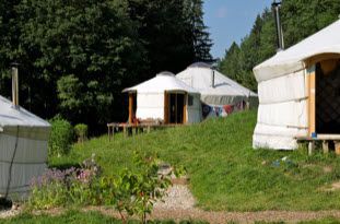 Auf einem grasbewachsenen Hügel steht eine Gruppe Zelte.