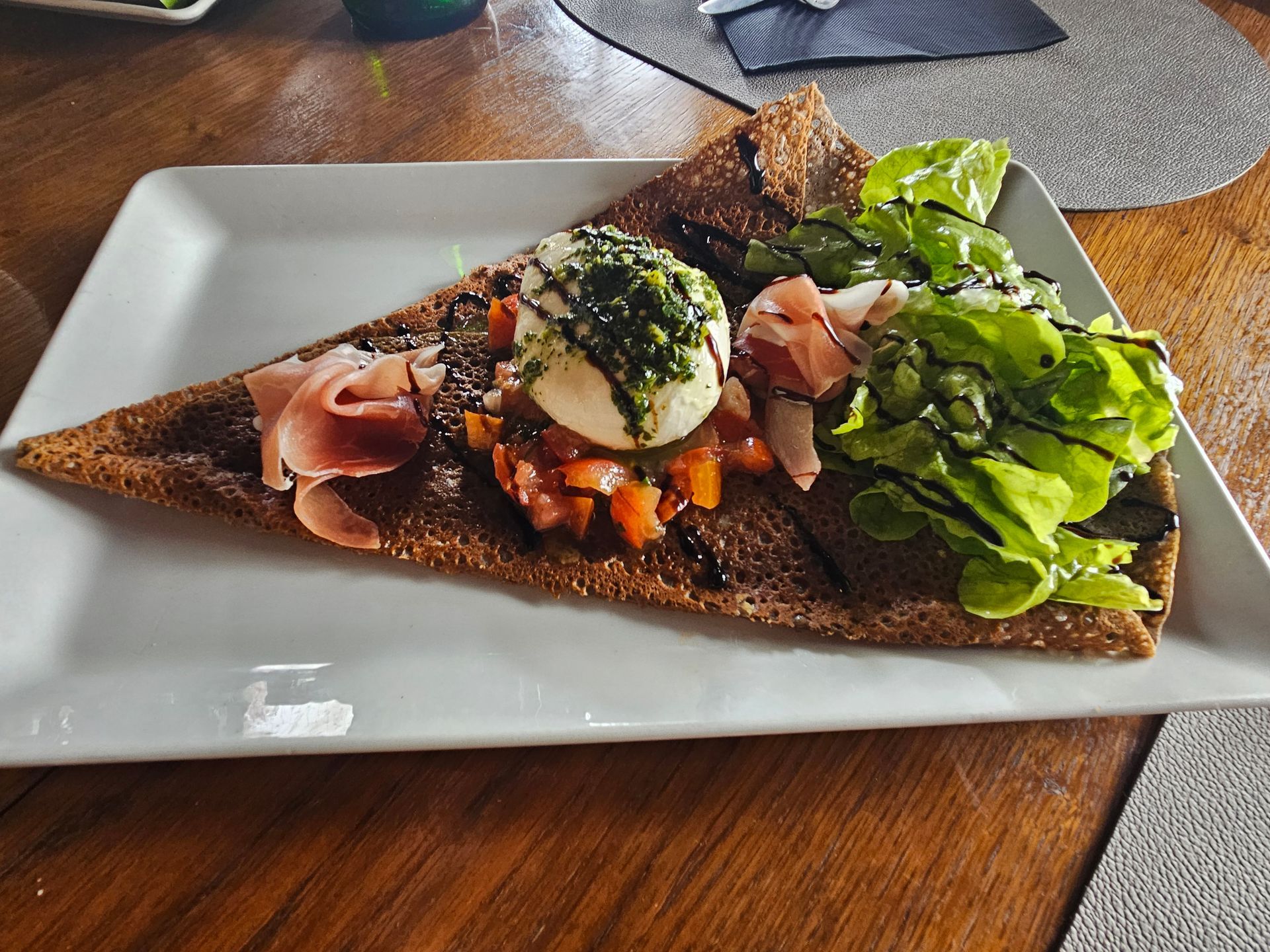 Galette salée avec brunoise de tomate, mozzarella, pesto, jambon cru et salade