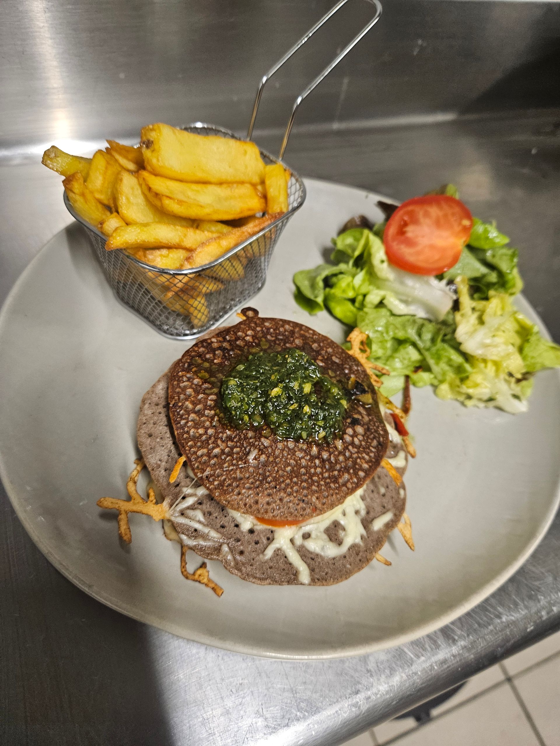 Burger de galette de sarrasin avec fromage fondu, frites et salade