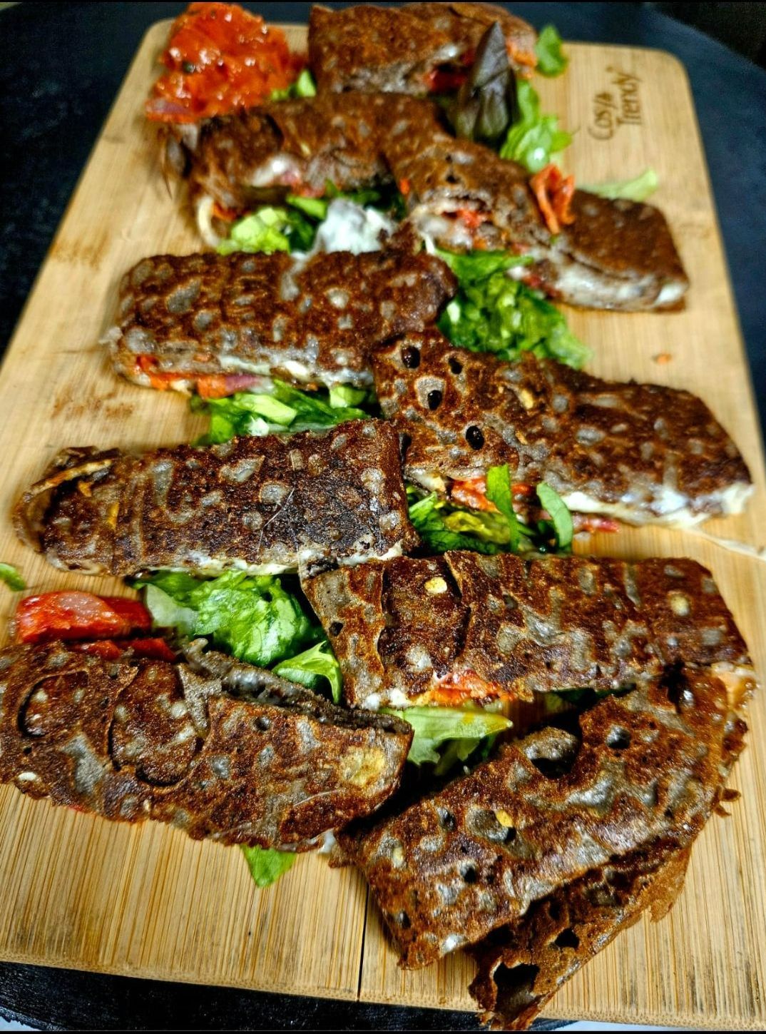 Galette roulée et farcie de légumes frais, présentée sur une planche en bois