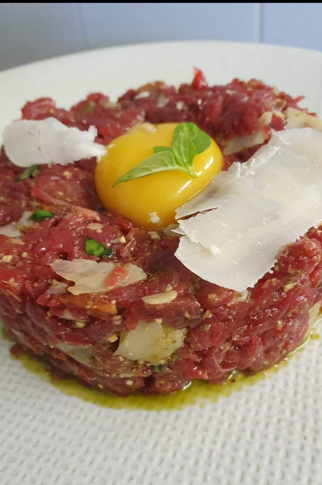 Tartare de bœuf avec jaune d'œuf, copeaux de parmesan et basilic