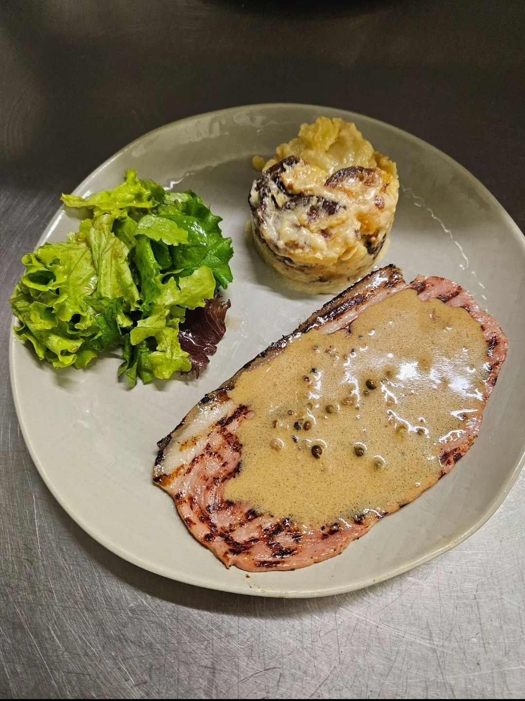 Assiette avec salade verte, gratin de pomme de terre et viande en sauce