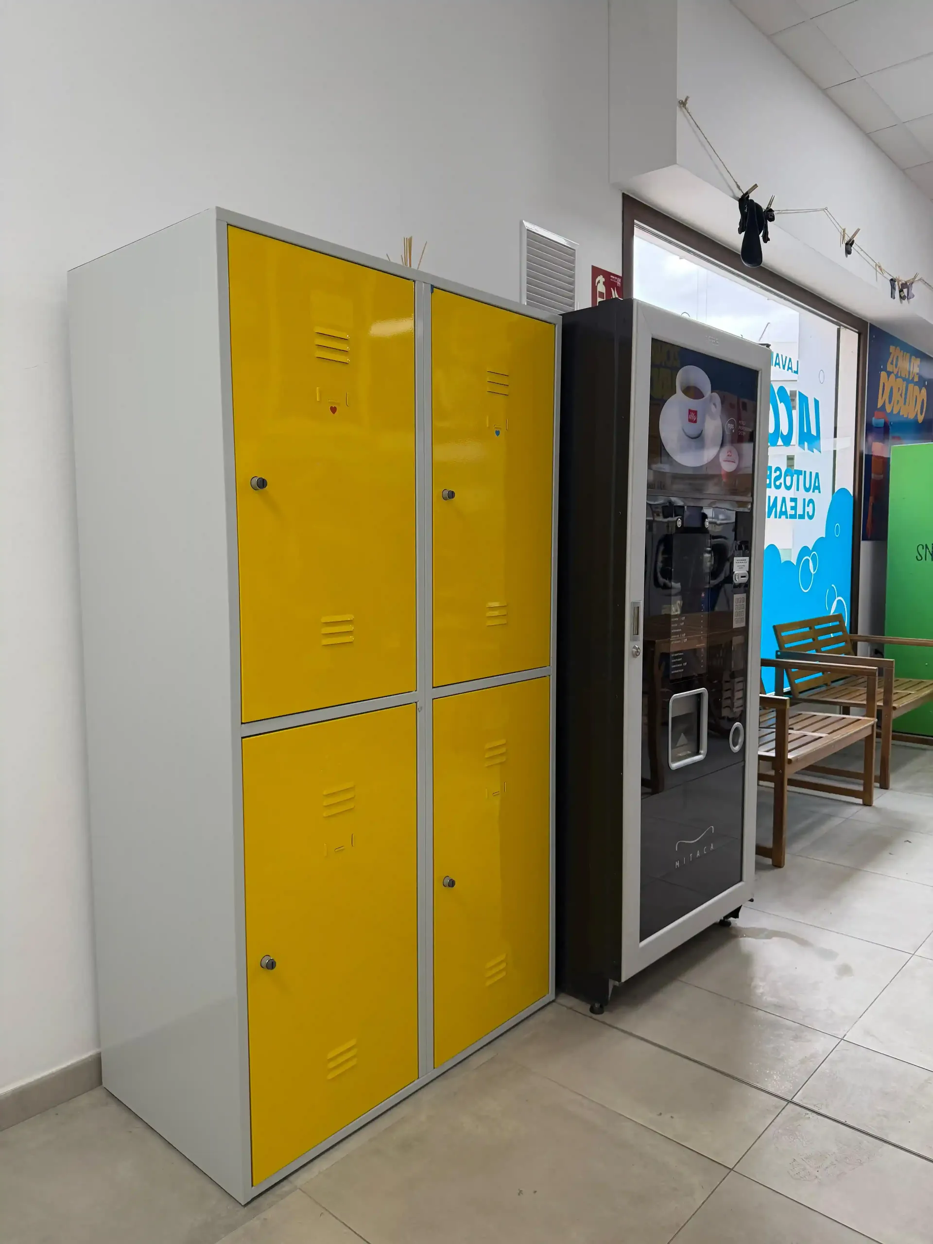 Taquillas amarillas junto a una máquina expendedora en un pasillo.