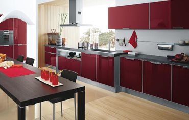 eine Küche mit roten Schränken und einem schwarzen Tisch