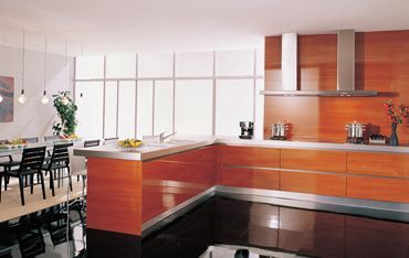 eine Küche mit Holzschränken , Edelstahlgeräten und einem Esstisch .