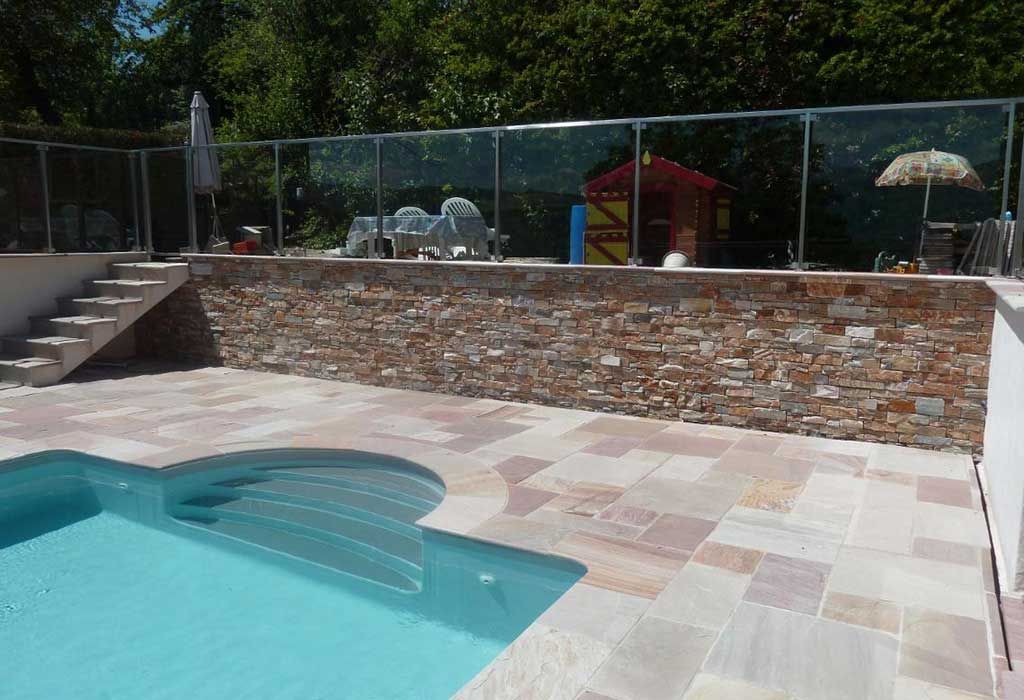 Terrasse de piscine en dallage avec muret en pierre