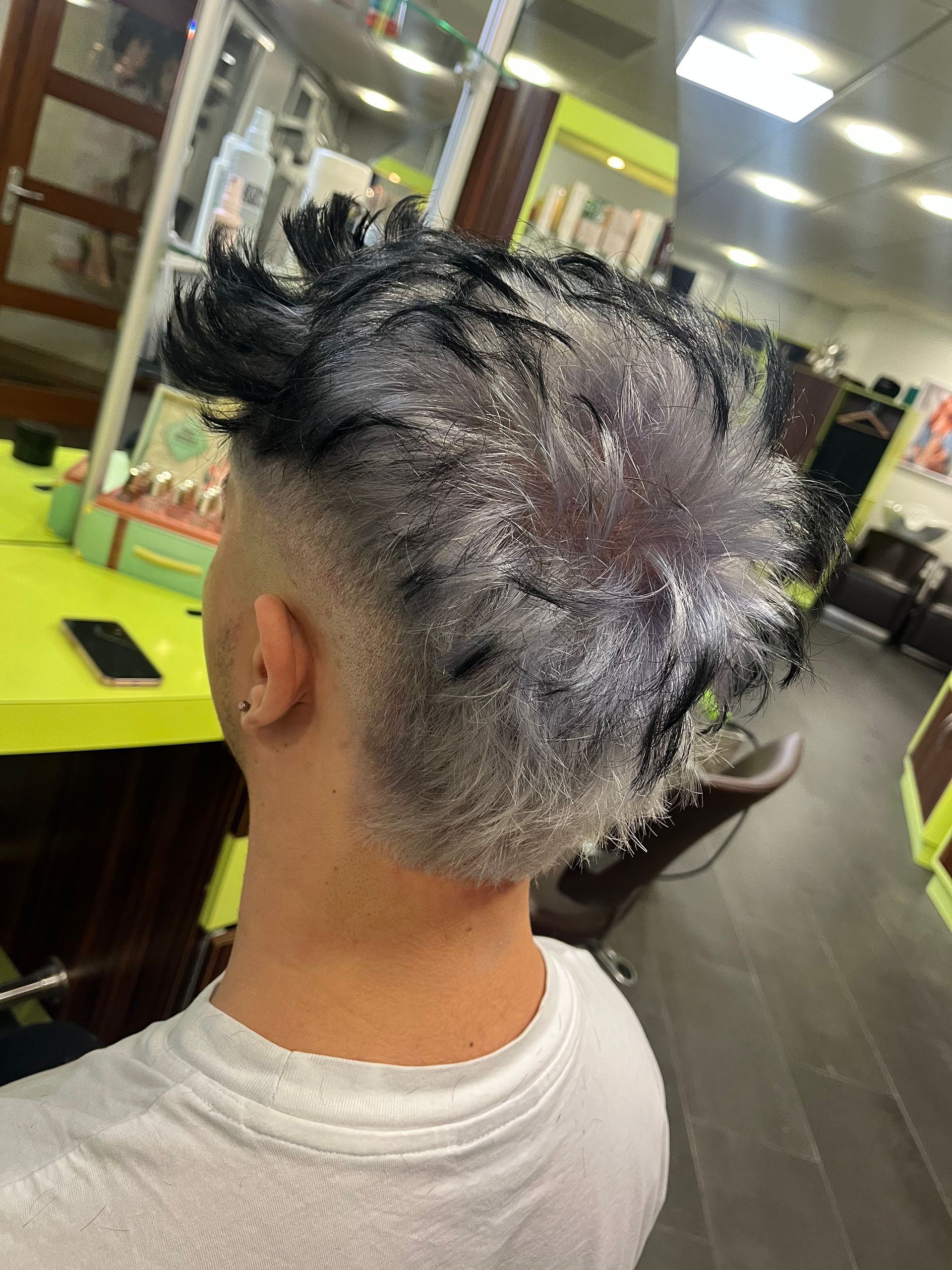Personne aux cheveux gris, noirs et blancs hérissés, avec une coupe dégradée, dans un salon de coiffure.