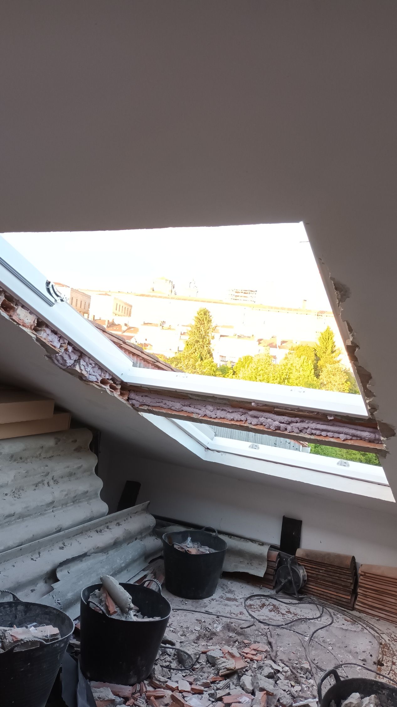 Vista interior de un tragaluz parcialmente demolido, que revela una brillante vista exterior. Se ven cubos y escombros.
