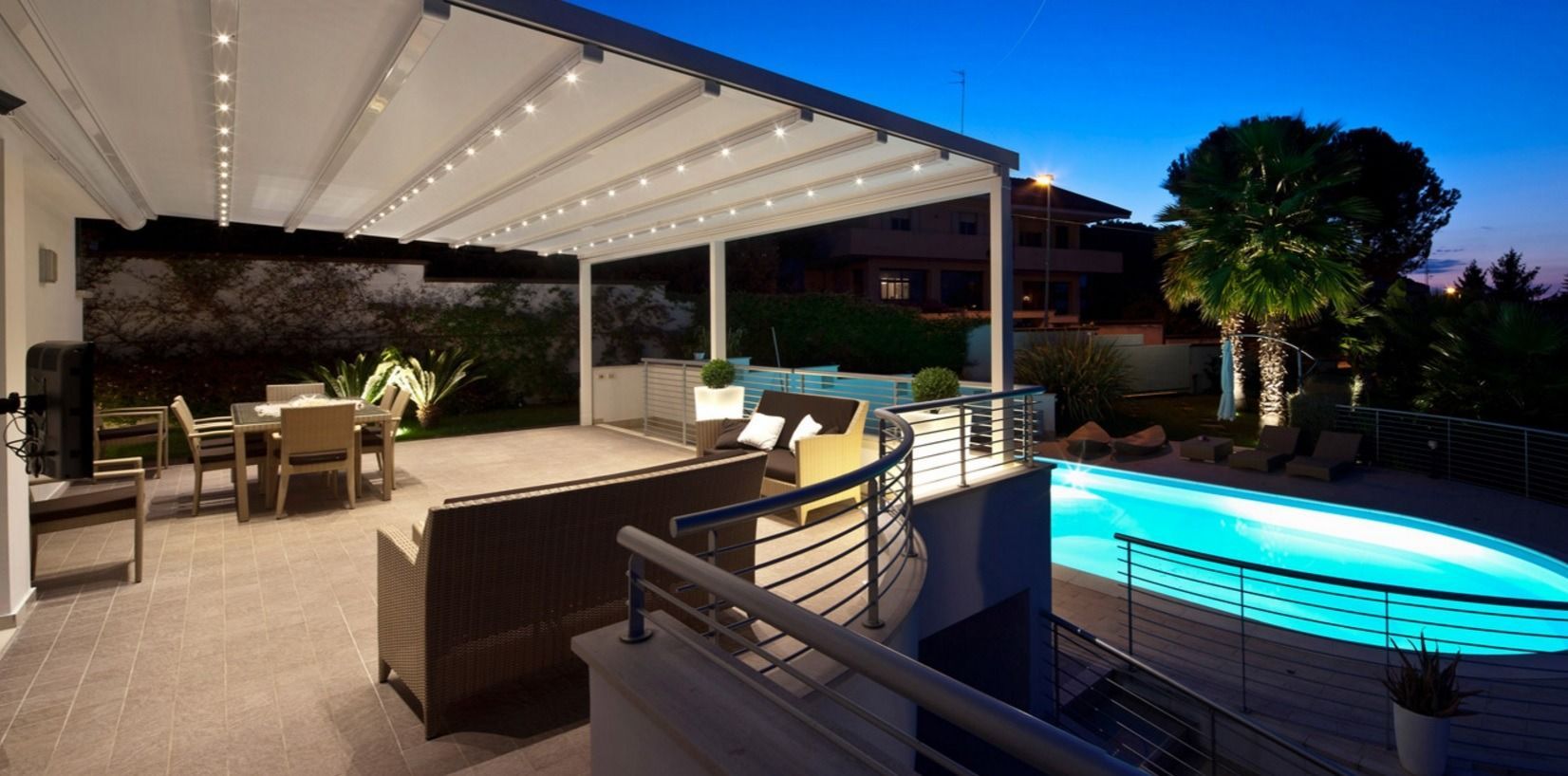 Un patio con pérgola y una piscina por la noche.