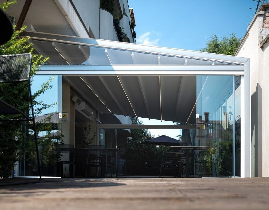 Una pérgola con puertas corredizas de vidrio se encuentra encima de una plataforma de madera.