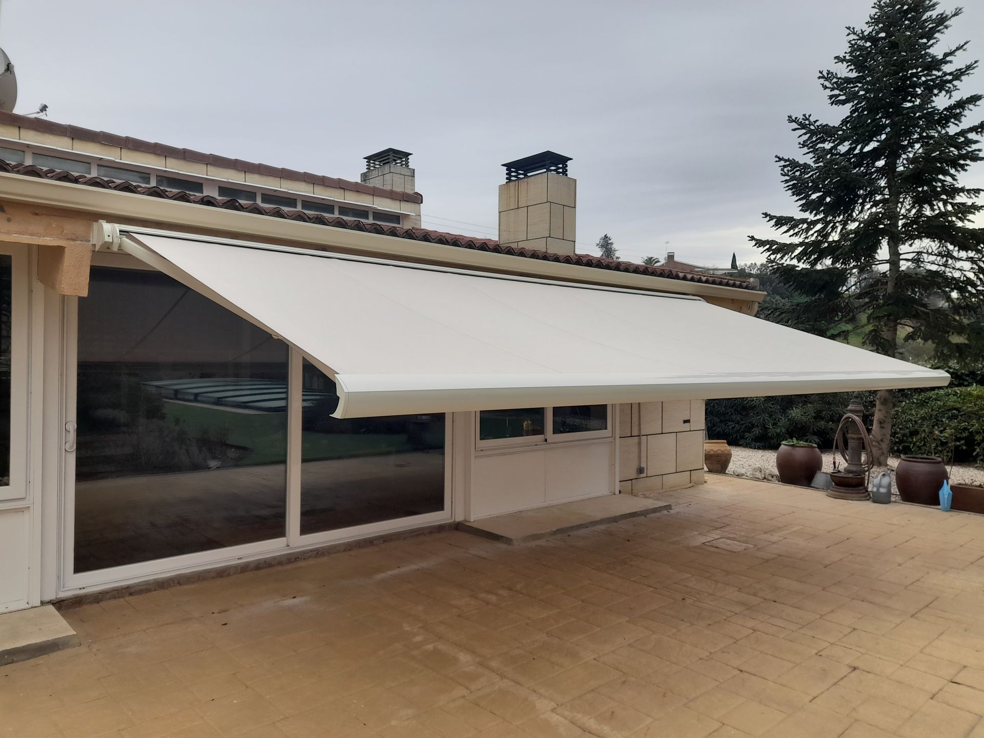 Un toldo blanco está sentado al costado de una casa.