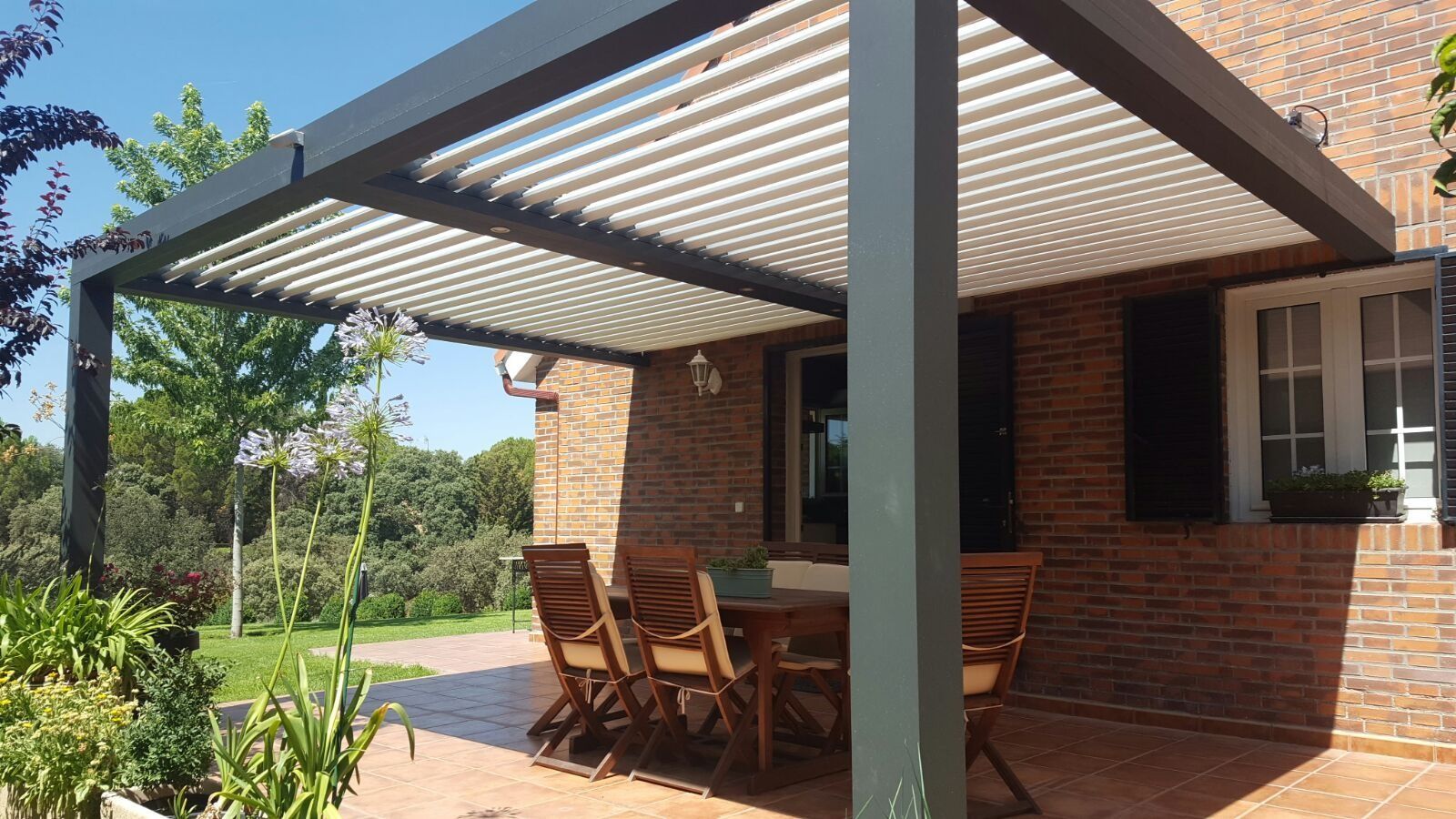 Un patio con una mesa y sillas bajo una pérgola.