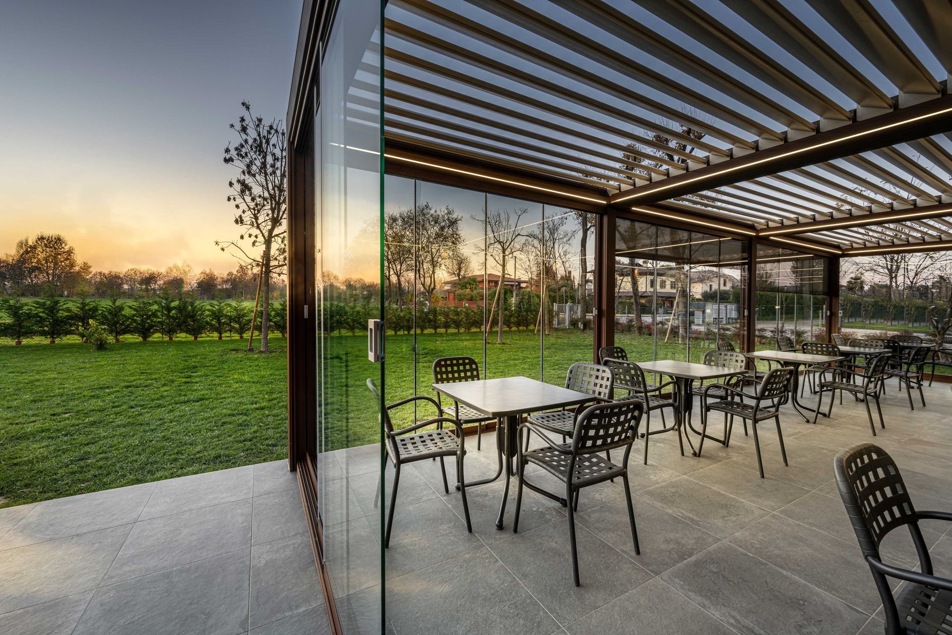 Un patio con mesas y sillas bajo una pérgola.