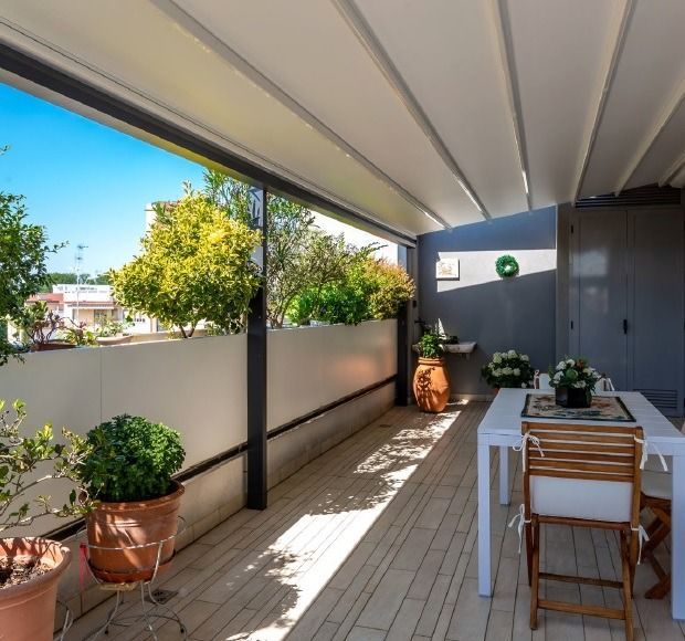 Un balcón con mesa, sillas y plantas en macetas.