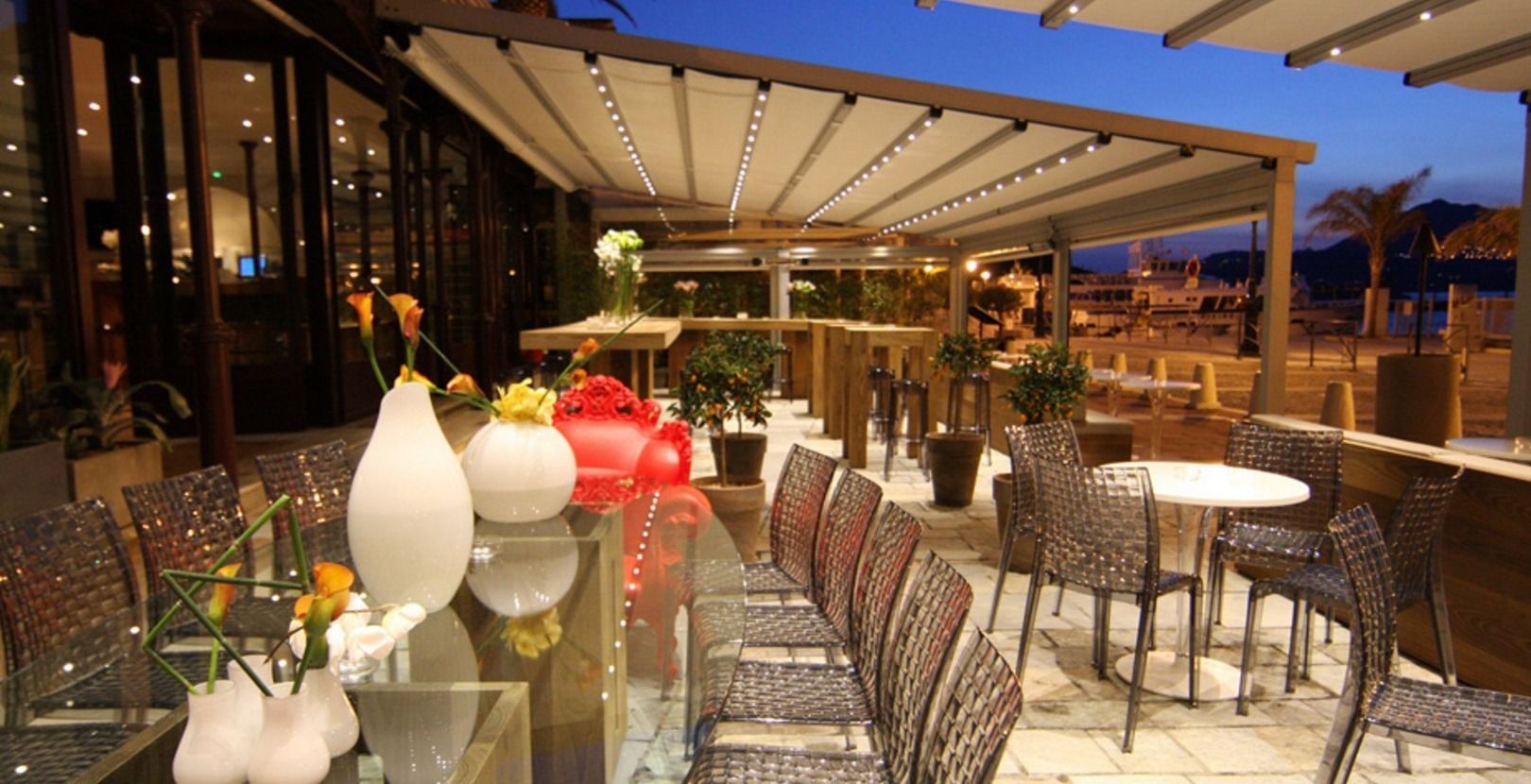 Un restaurante con mesas y sillas y jarrones en la mesa.