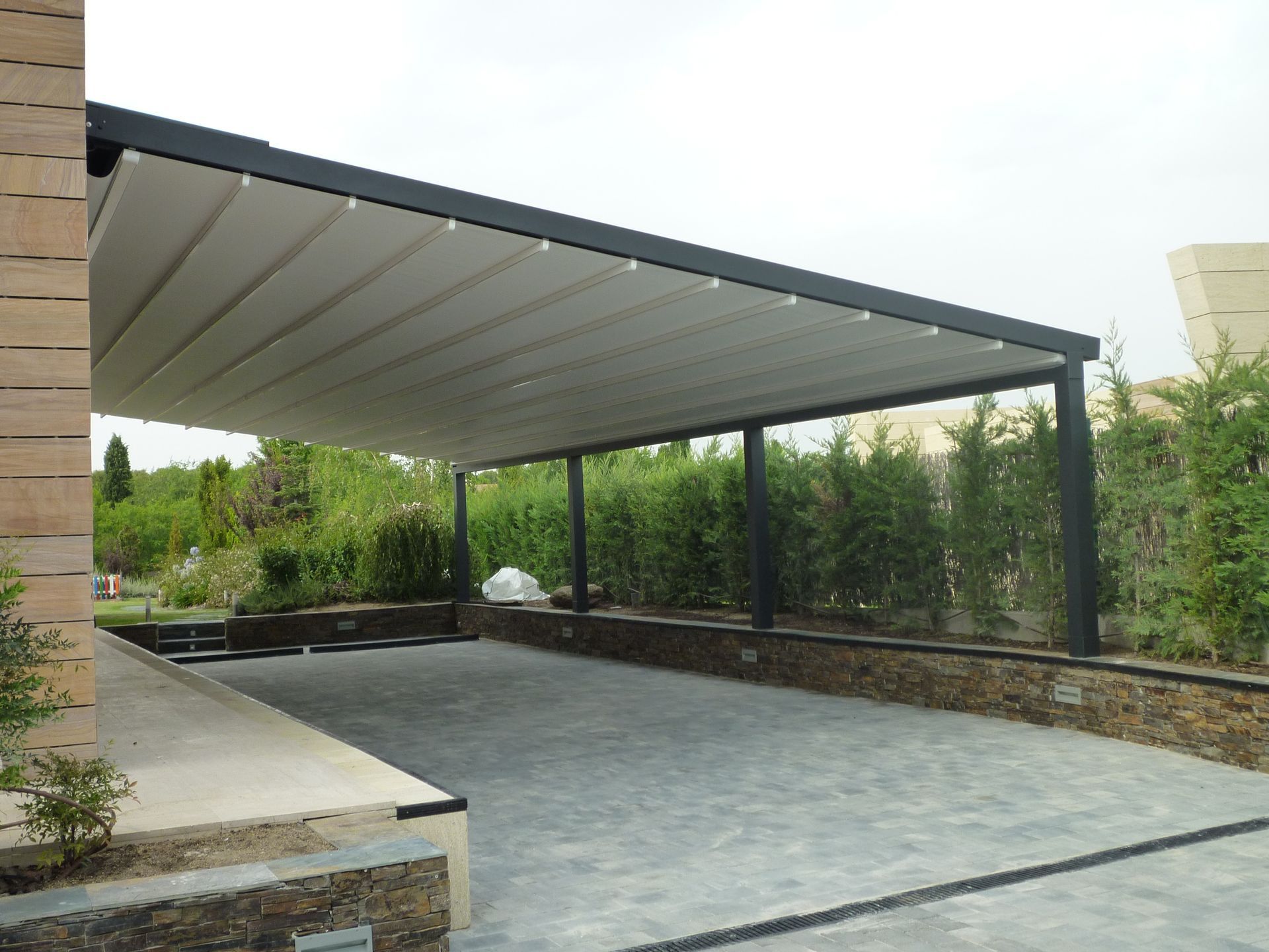 Una cochera con un toldo encima y un muro de piedra