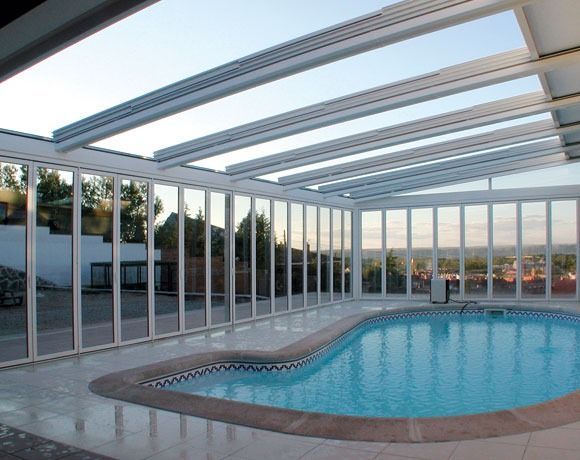 Una gran piscina cubierta bajo un techo de cristal