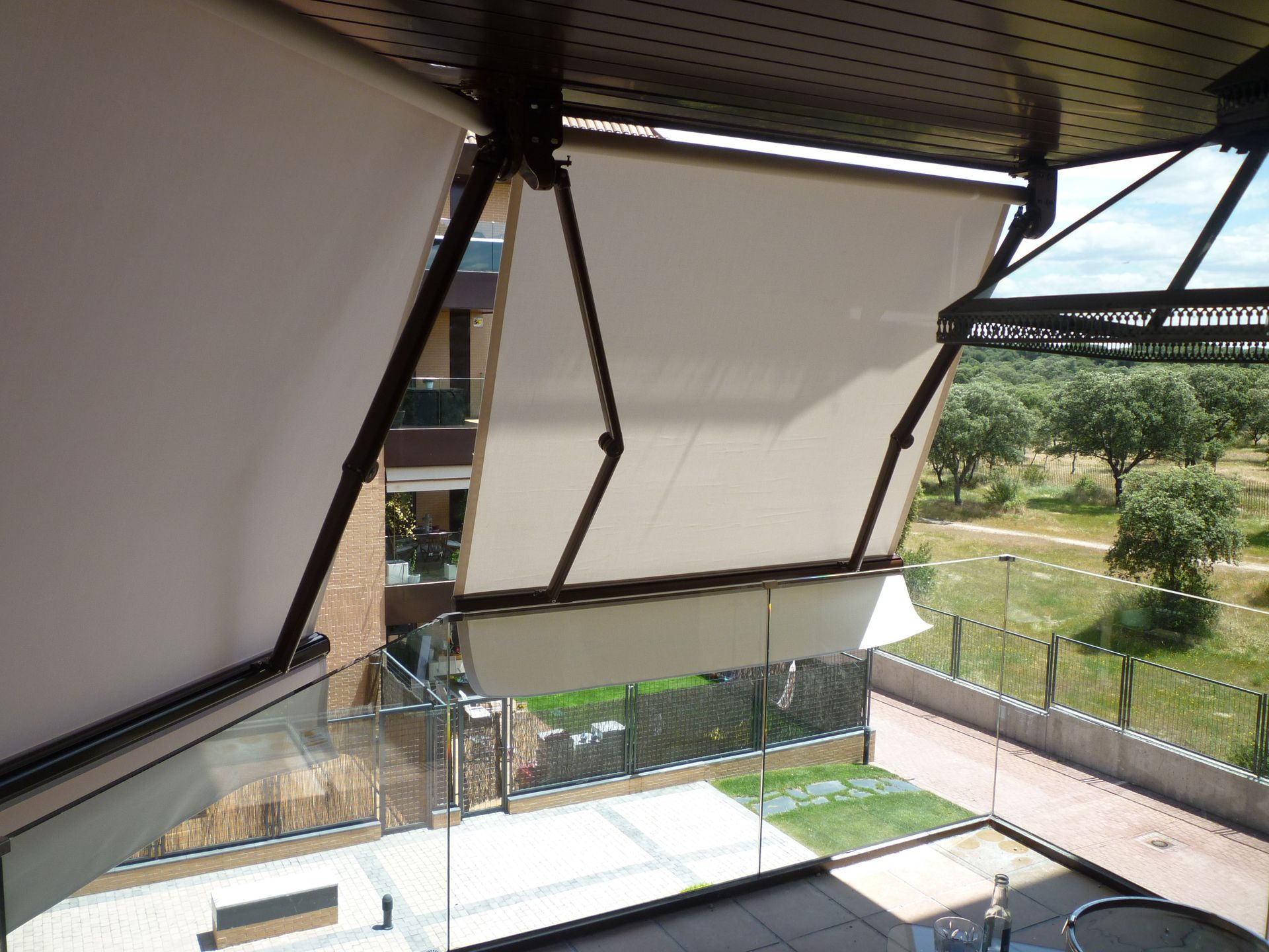 Un balcón con toldo blanco y vista a un parque.
