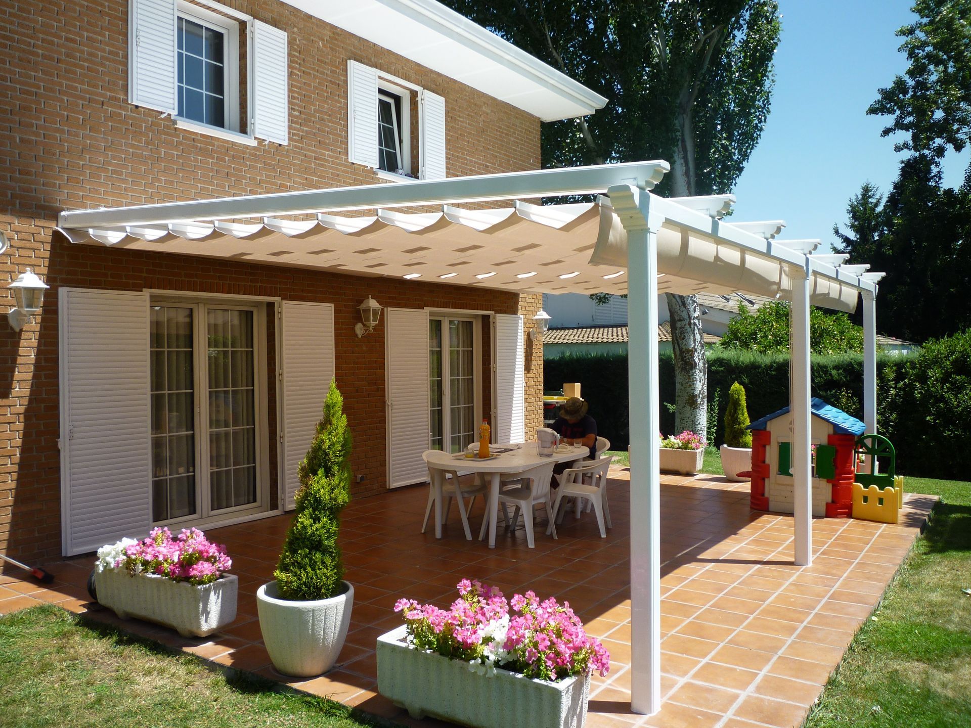 Una casa con un patio con una mesa y sillas bajo un dosel