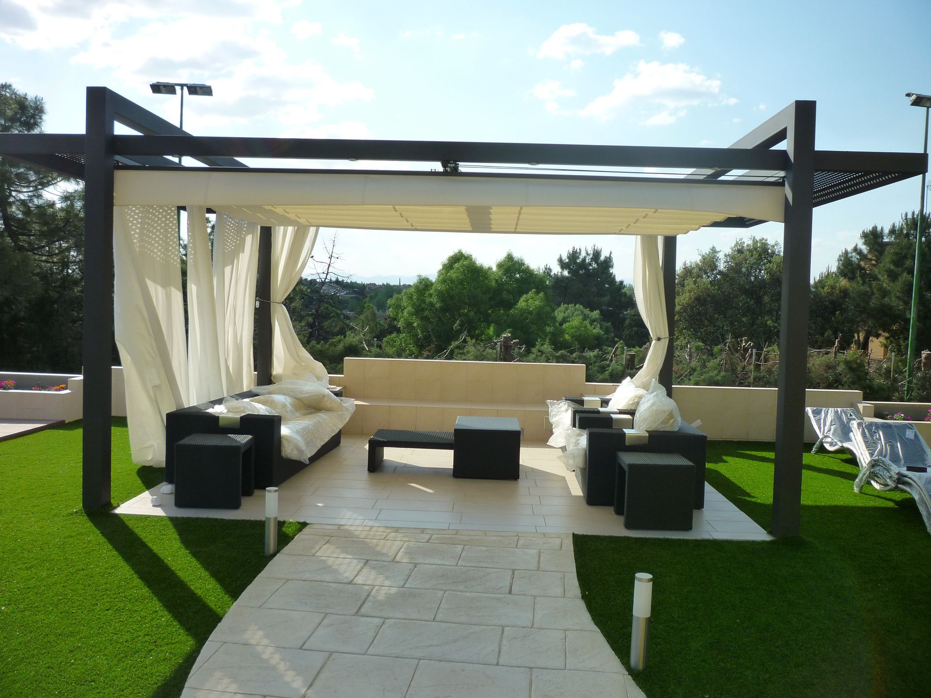 Una pérgola con un sofá y sillas debajo.