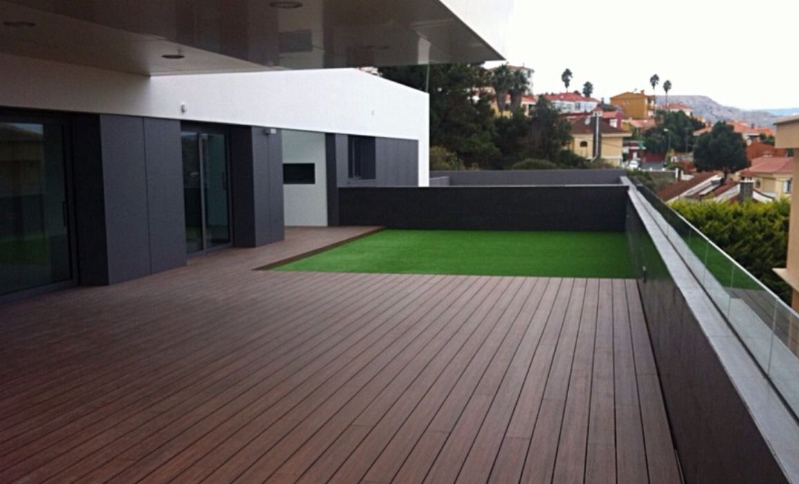 Un balcón con terraza de madera y barandilla de cristal.