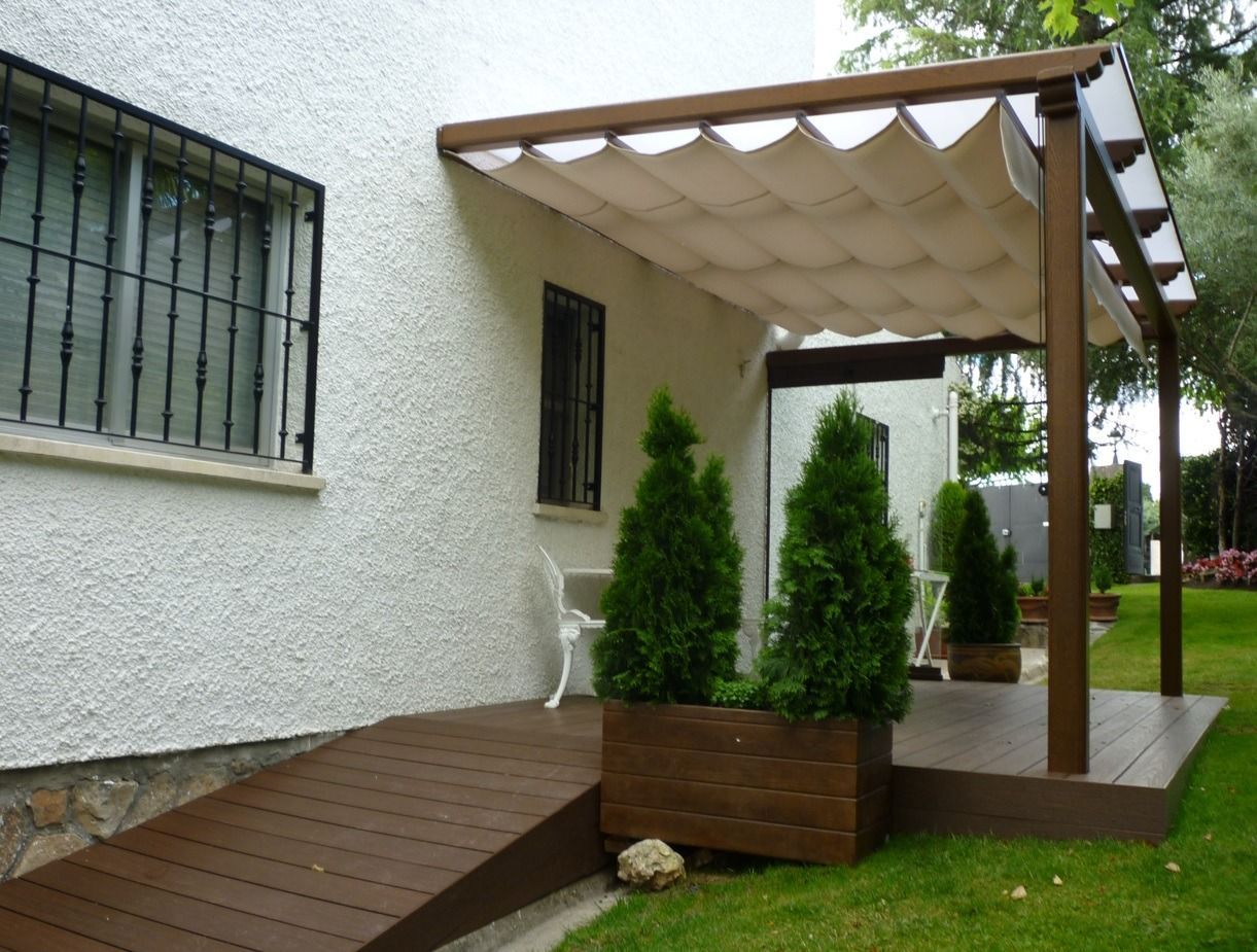 Una casa blanca con una terraza de madera y un dosel sobre ella.