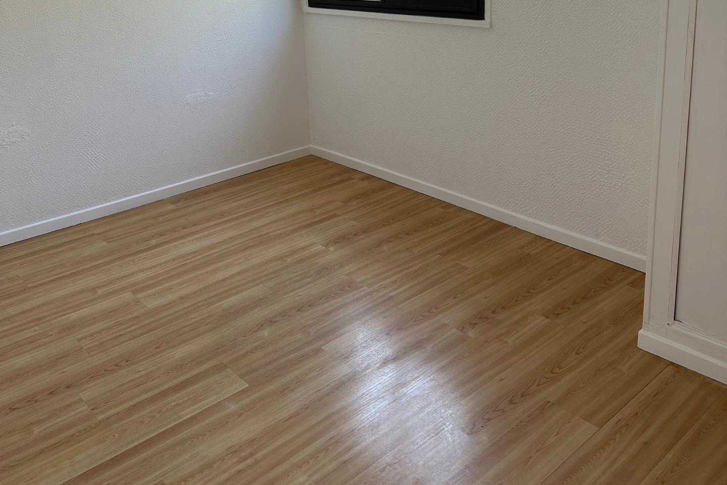 Une pièce vide avec un plancher en bois et des murs blancs.