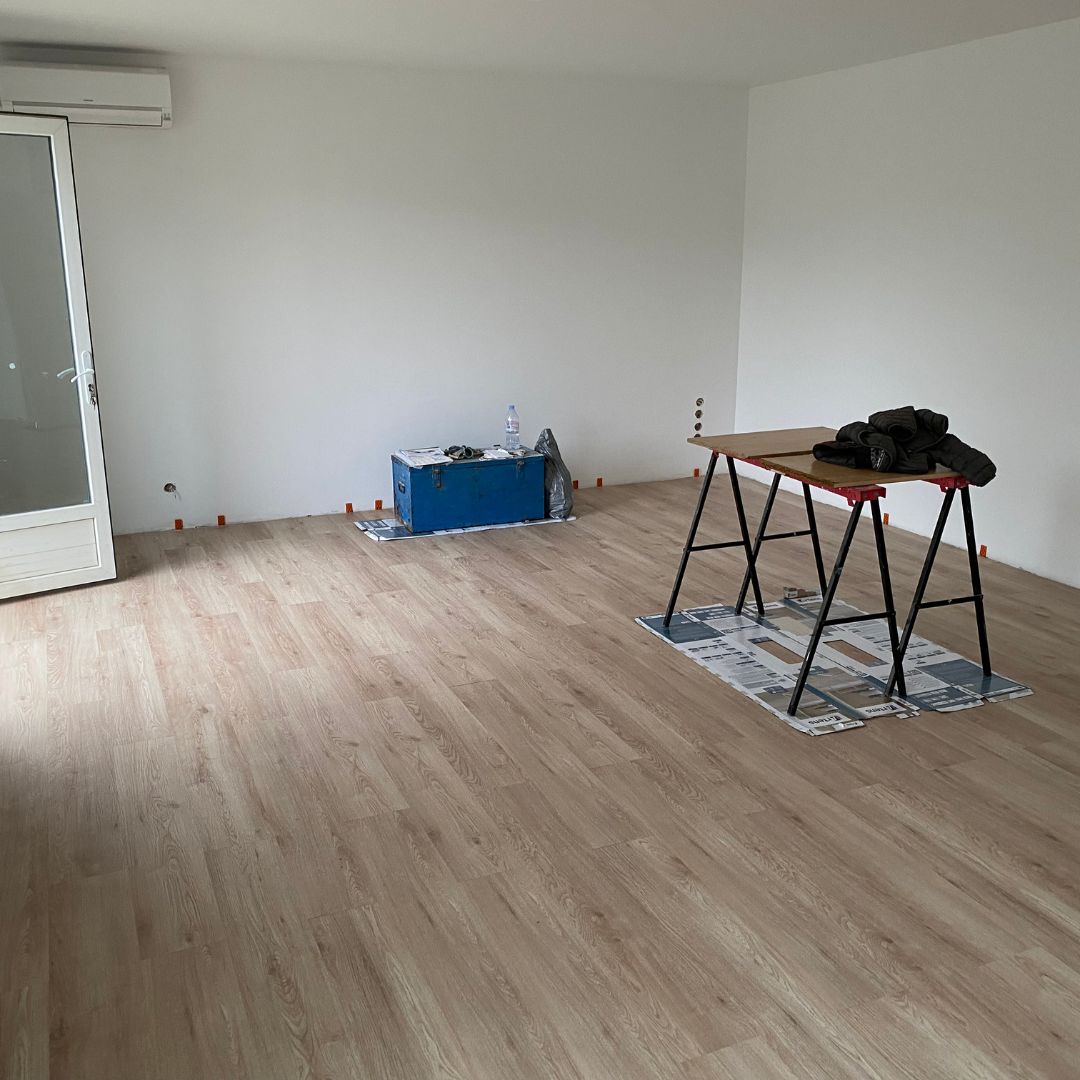 Un couloir avec une porte noire et un panneau de sortie rouge.