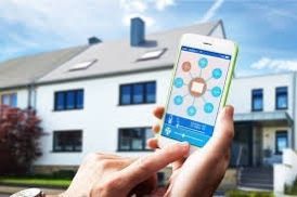 Une personne tenant un smartphone contrôle une maison intelligente ; une maison blanche est en arrière-plan.