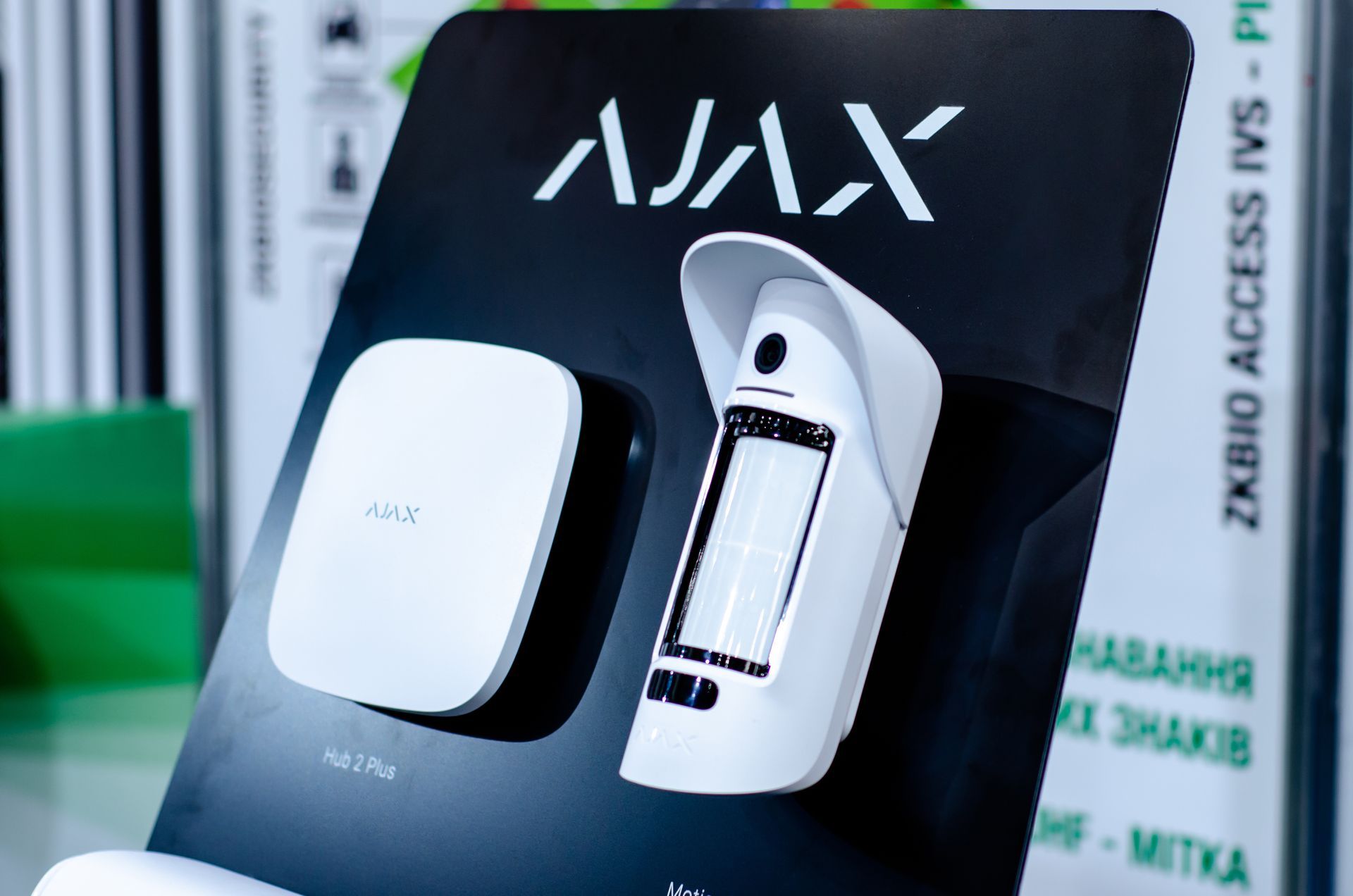 Écran noir avec le logo « AJAX », comportant un appareil rectangulaire blanc et un appareil blanc semblable à une caméra.