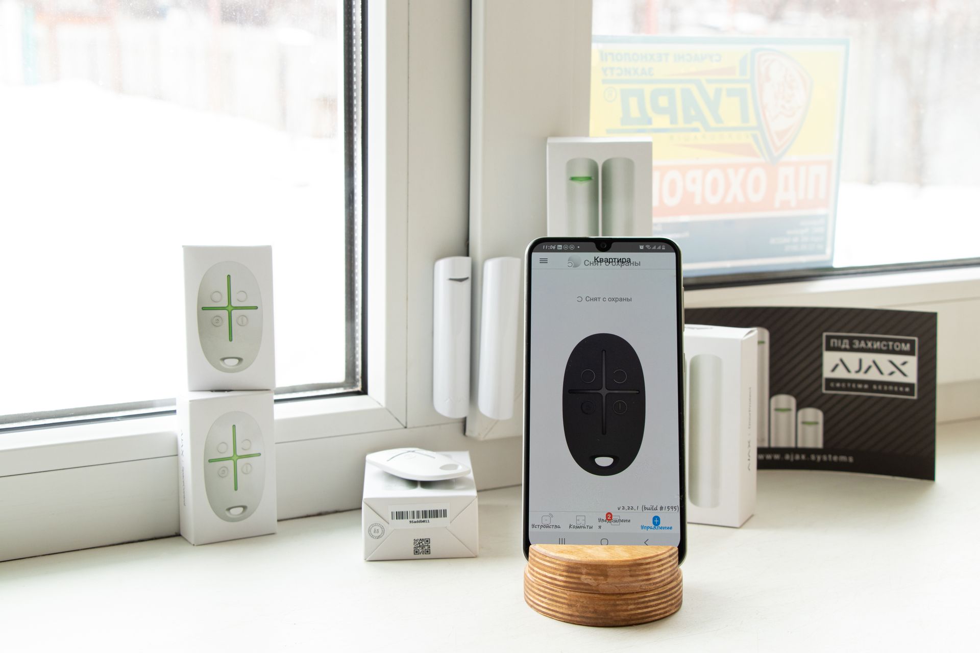 Composants du système de sécurité, smartphone affichant l'interface de l'application, sur un rebord de fenêtre.