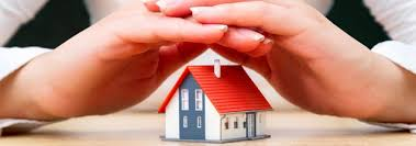 Mains abritant une maison miniature au toit rouge, symbolisant la protection ou l'assurance de la maison.