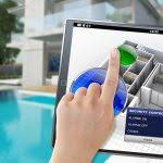 Une personne utilise une tablette pour contrôler un système de sécurité domestique près d'une piscine.