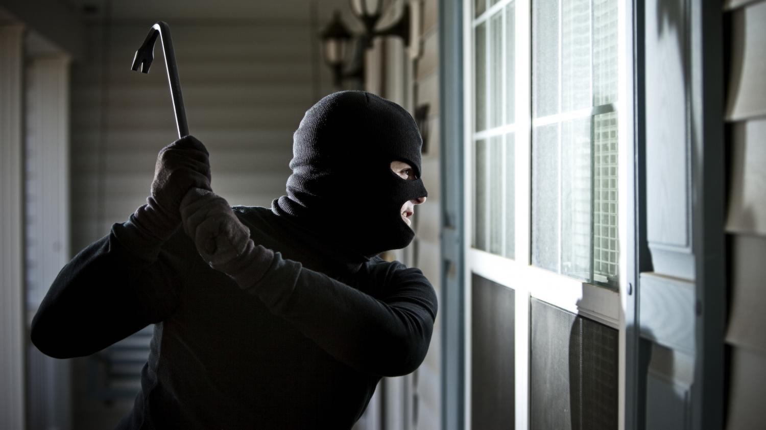 Un homme cagoulé s'introduit dans une maison avec un pied-de-biche.