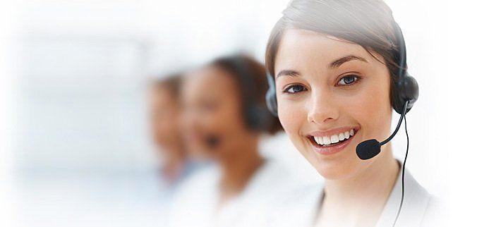 Femme souriante avec un casque dans un centre d'appels, collègues flous en arrière-plan.