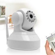 Caméra de sécurité blanche avec antenne, à l'intérieur. Une personne tient un téléphone pour la contrôler à distance.