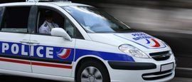 Une voiture de police française circule dans la rue.