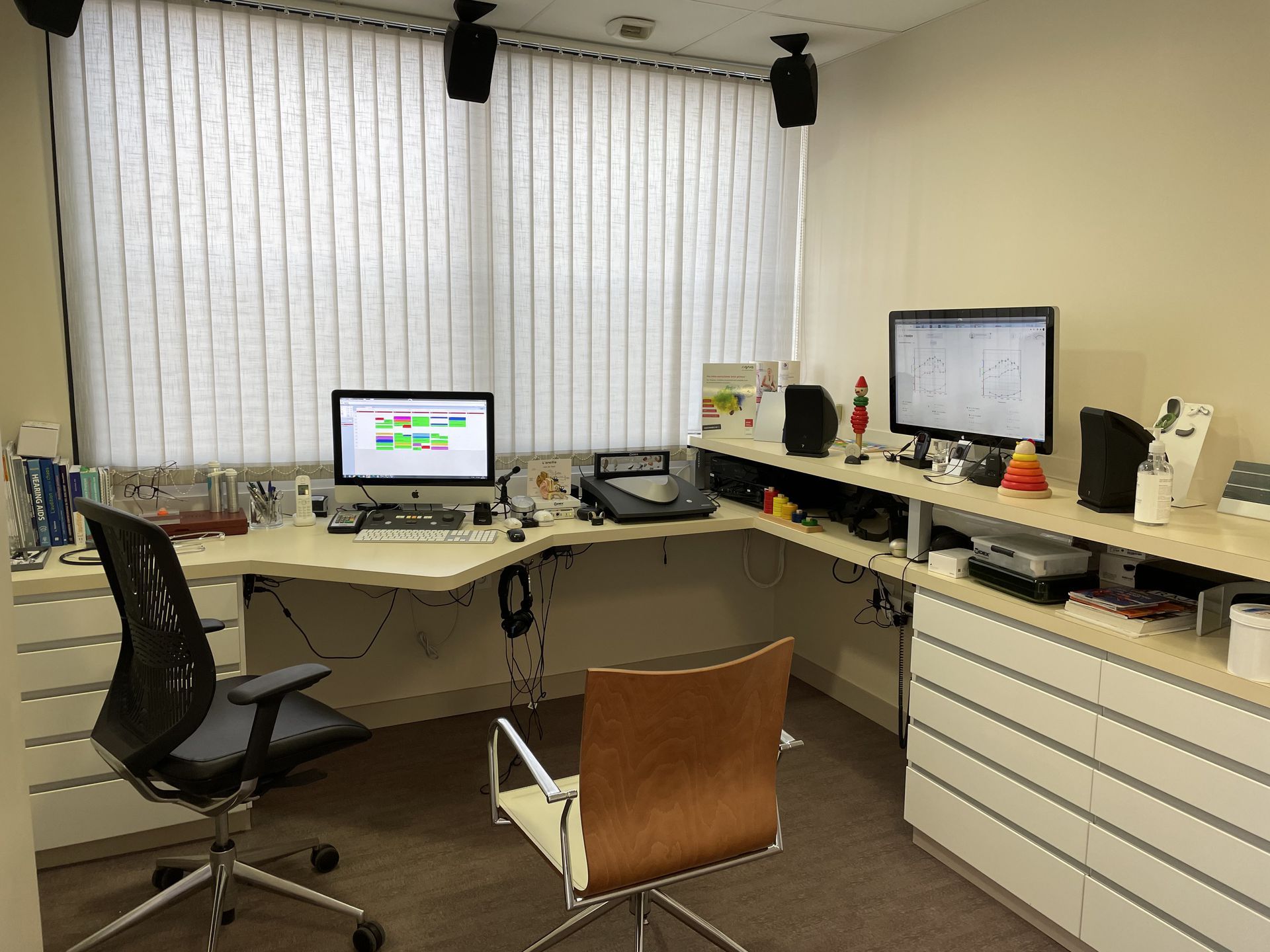 Espace de travail de bureau moderne avec bureaux, ordinateurs, chaises et armoires de rangement dans une pièce beige
