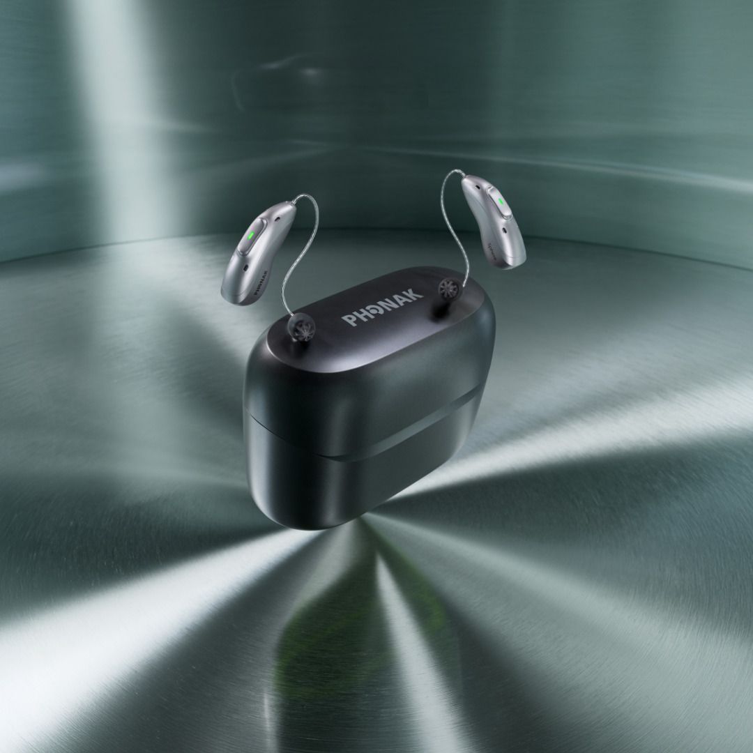 Écouteurs sans fil noirs dans un boîtier de charge ouvert, posés sur une surface métallique.