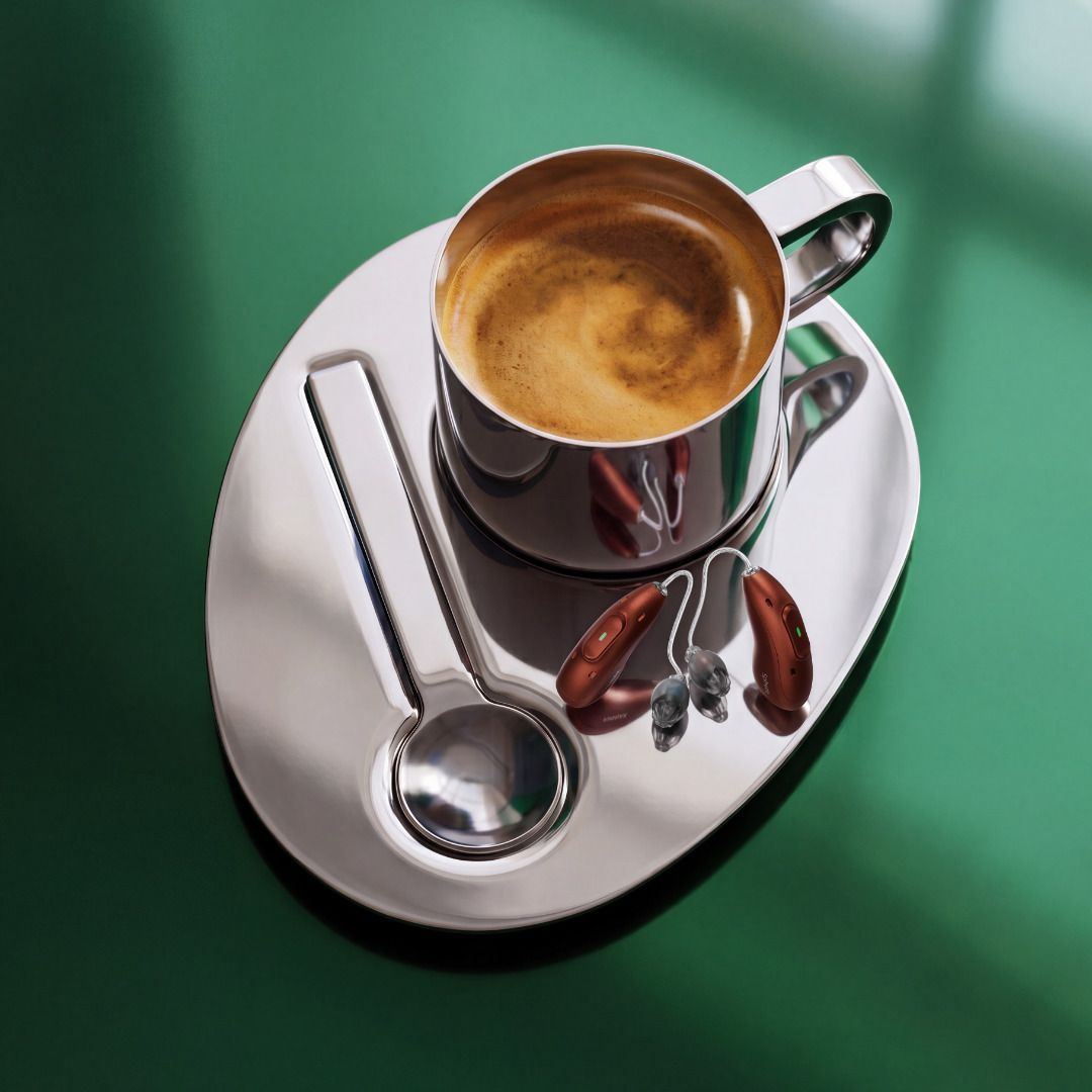 Vue de dessus d’une tasse de café posée sur une soucoupe, avec une cuillère et des grains de café sur un fond vert