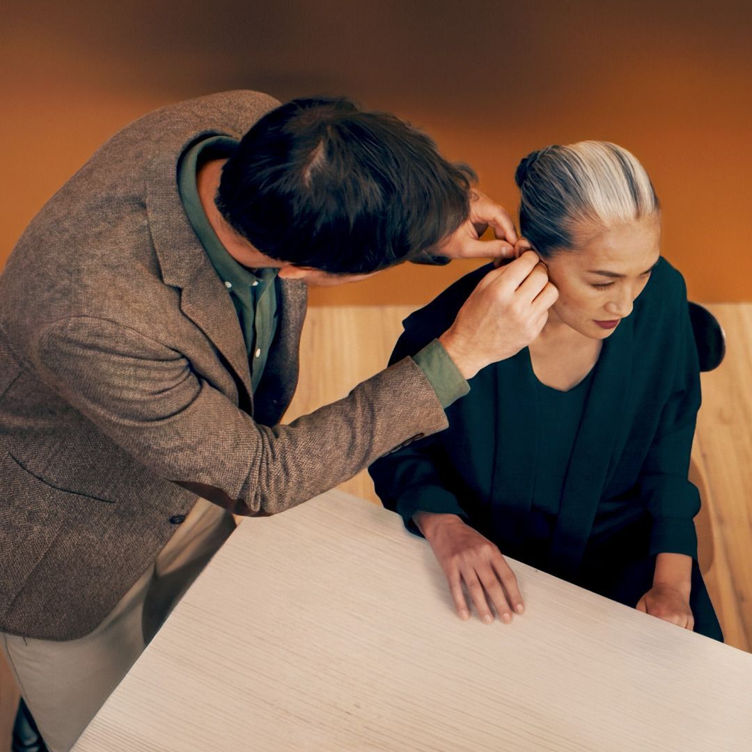 Une personne coiffant quelqu’un d’autre à une table, avec un peigne et une coiffure tressée élégante.