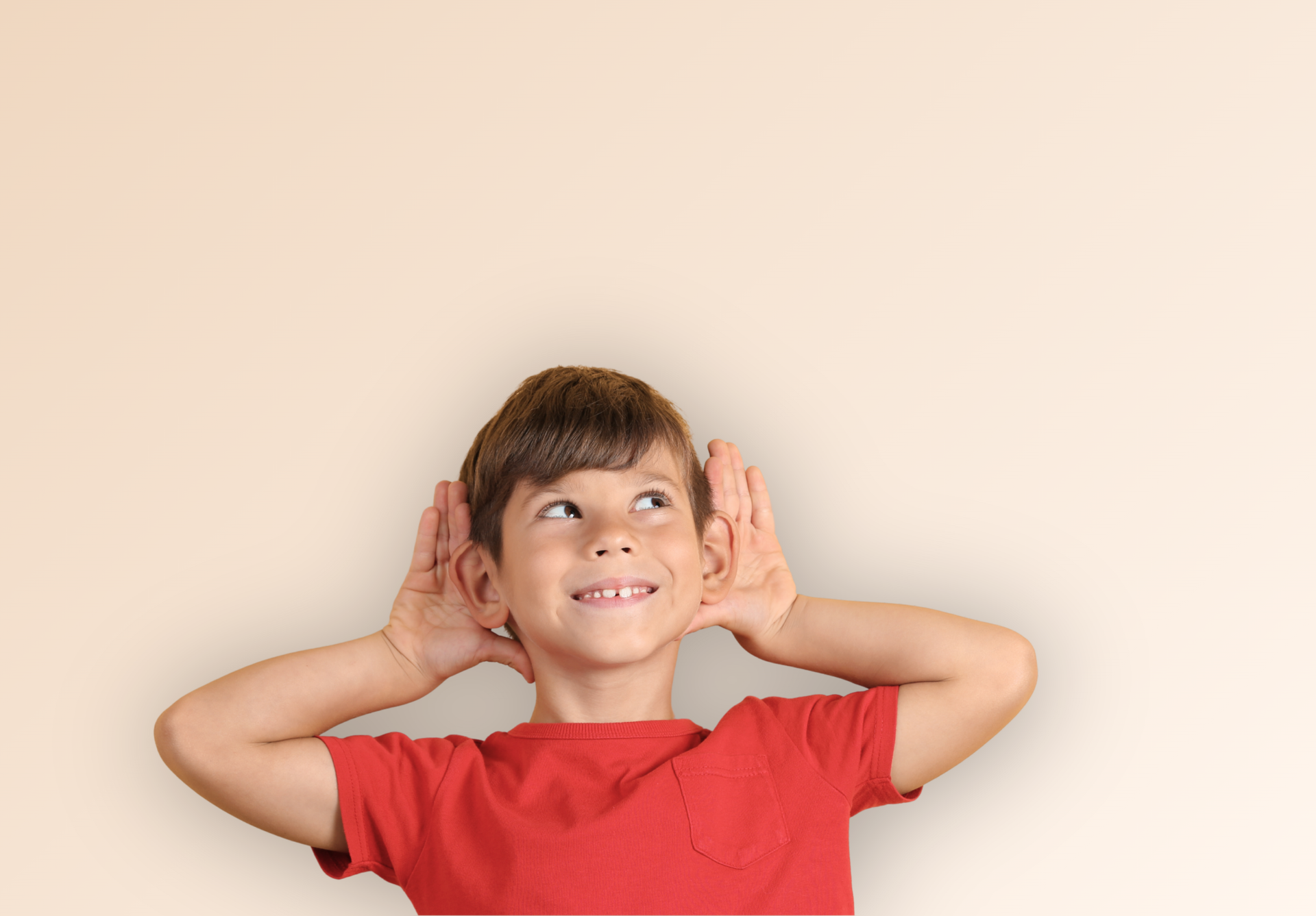 Enfant souriant en chemise rouge, les mains derrière les oreilles, sur fond beige uni