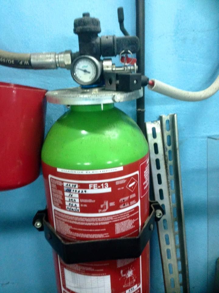 Un extintor verde y rojo está pegado a una pared azul.