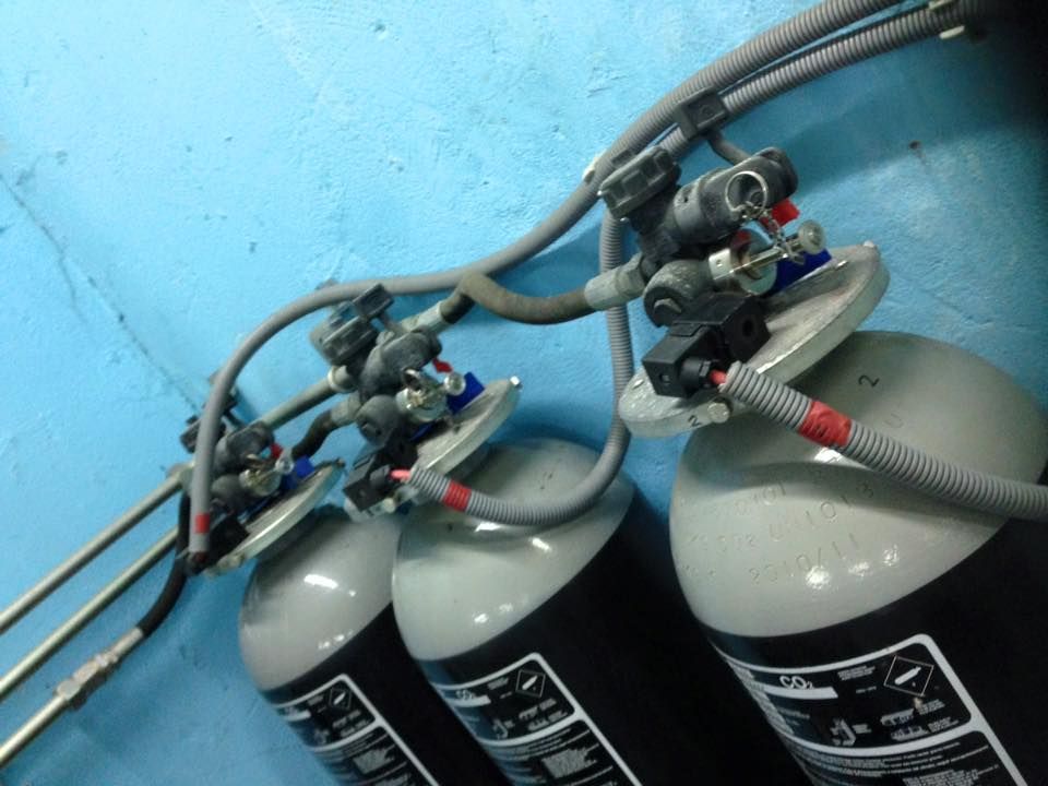 Tres extintores están fijados a una pared azul.