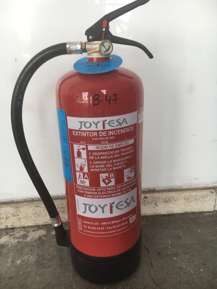 Un extintor de incendios Joyfesa rojo está tirado en el suelo.